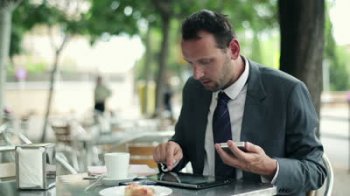 stock-footage-businessman-working-with-tablet-and-smartphone-in-cafe