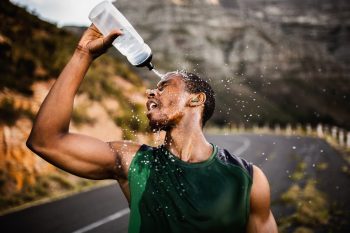 African American athlete splashing water on his face after excer